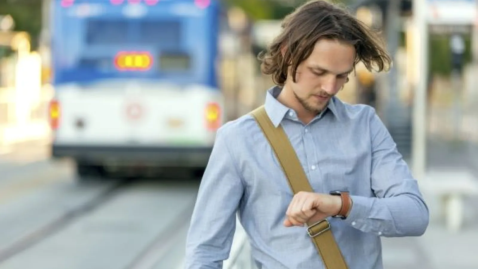 A man looks at his watch at a bus stop