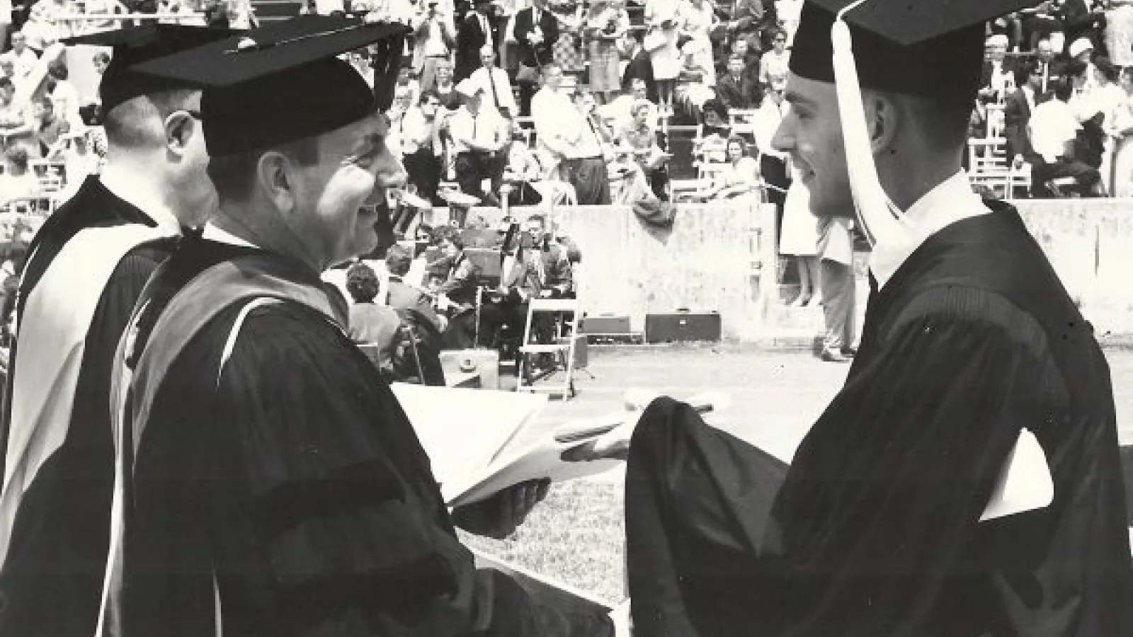 a student accepts his diploma in a black and white photo
