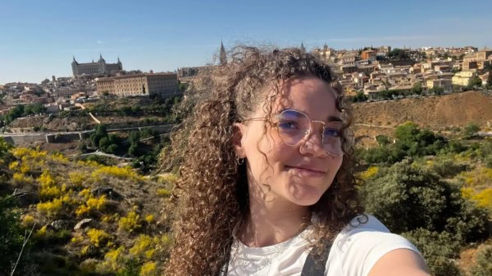 a young woman with curly brown hair in a Spanish landscape