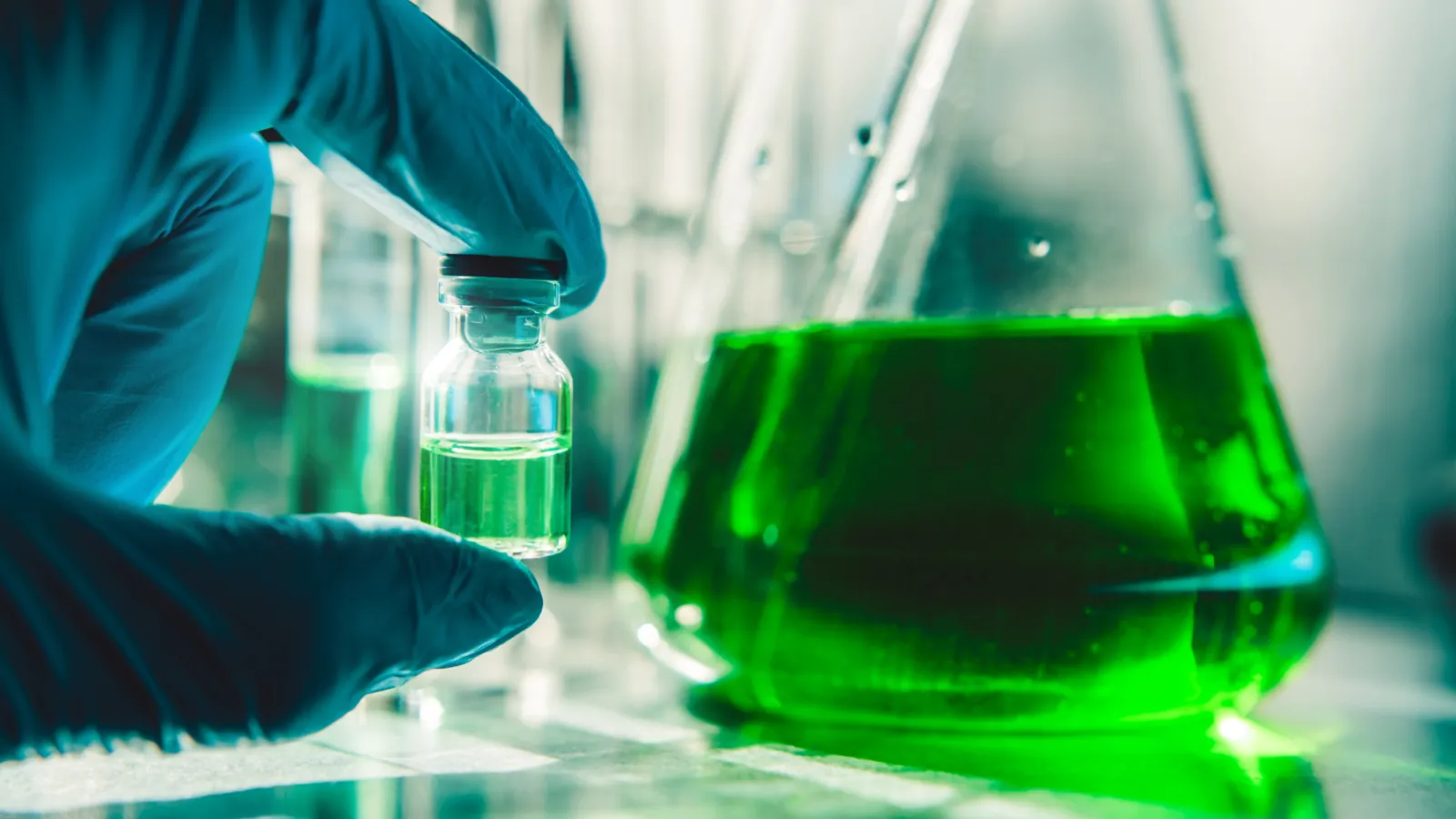 Beaker and vial with green liquid inside