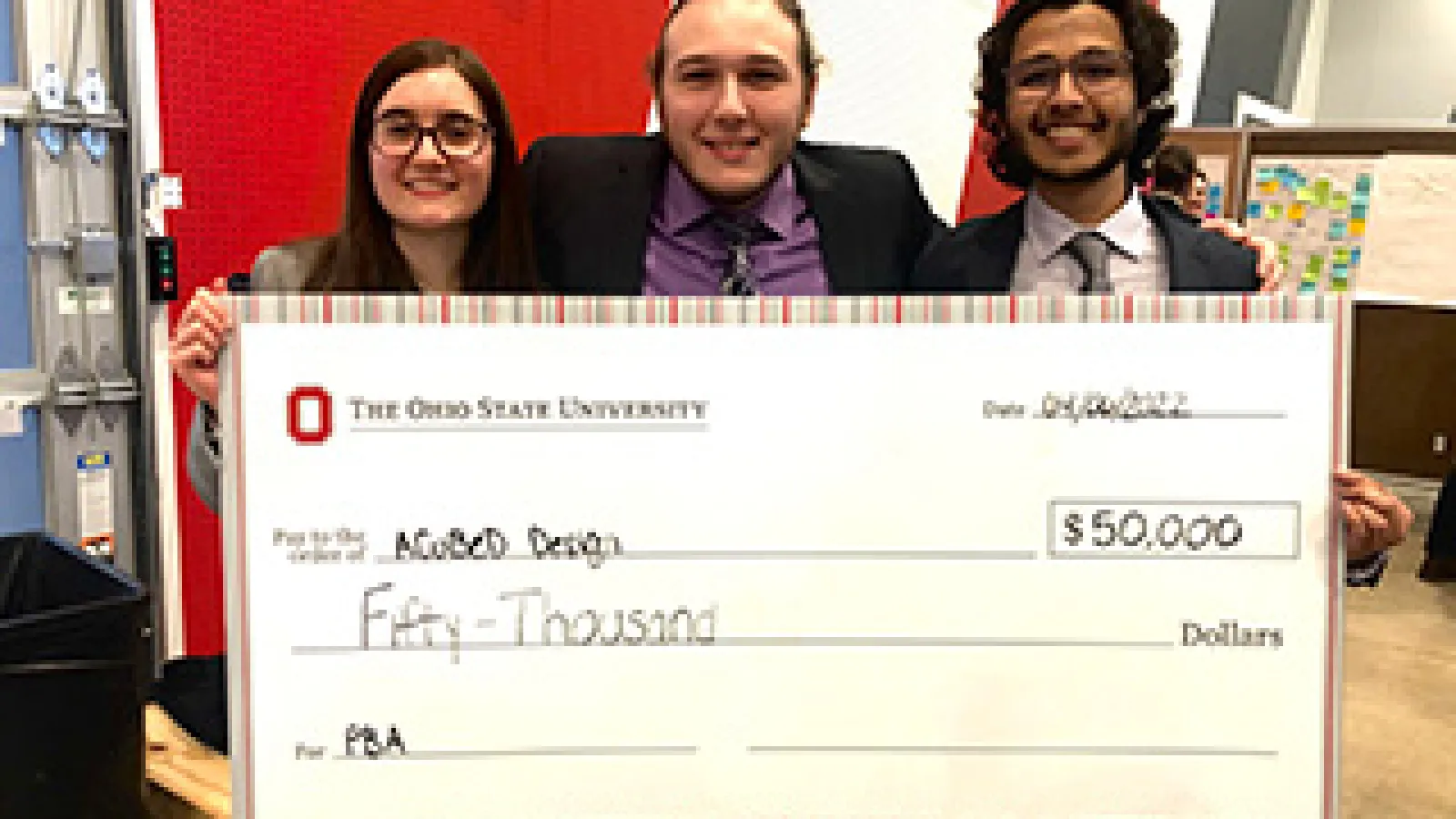 The A Cubed Design team members holding a large check